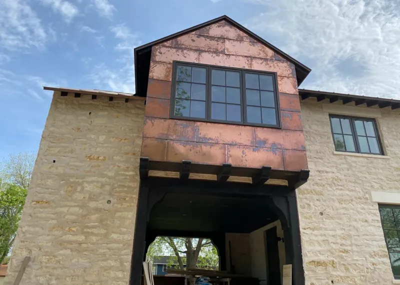 Copper metal panel facade on a stone building for Skylight Installation in Baxter Village